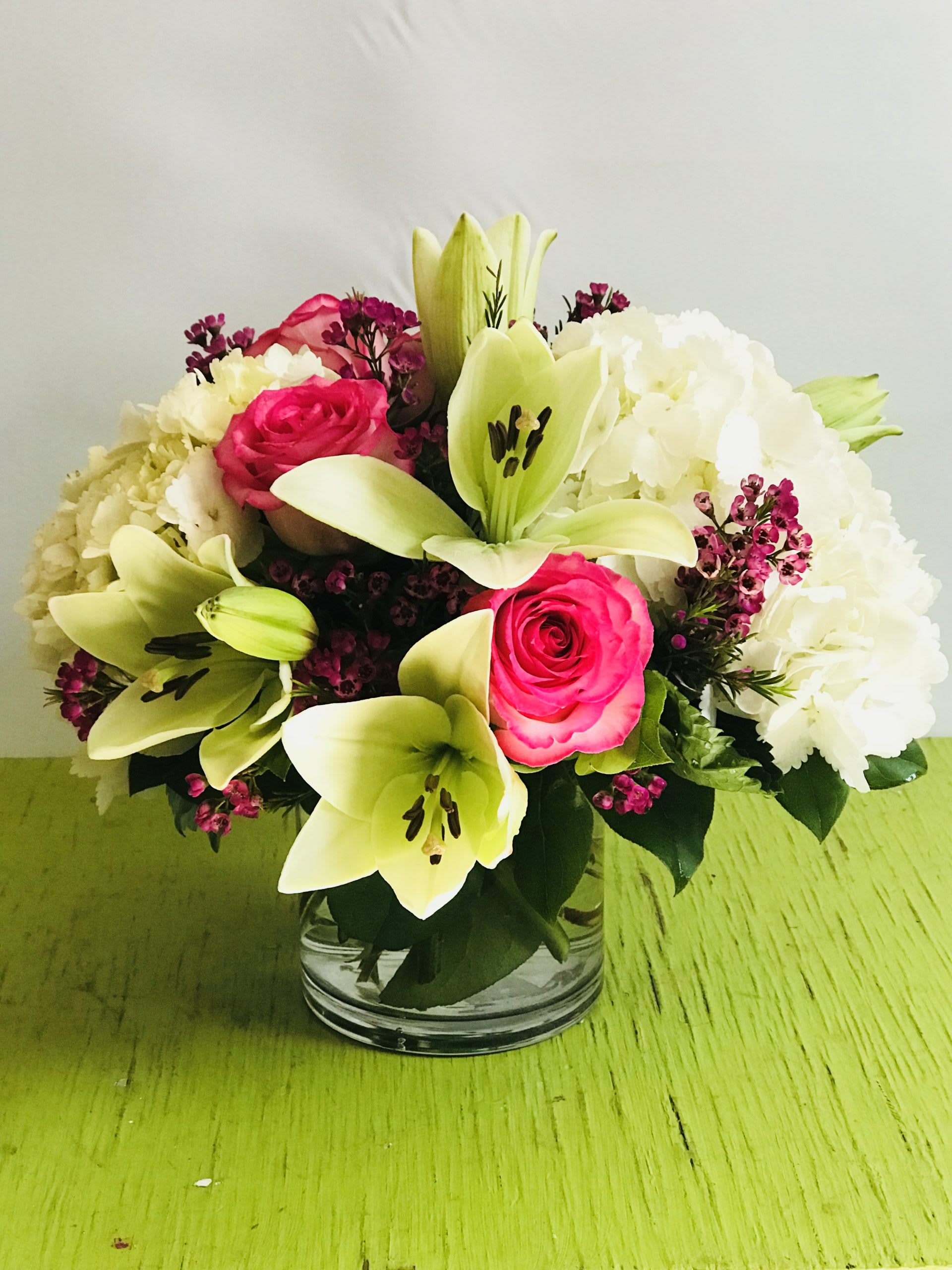 Bouquet of pink roses, white lilies, and white hydrangeas in a glass vase