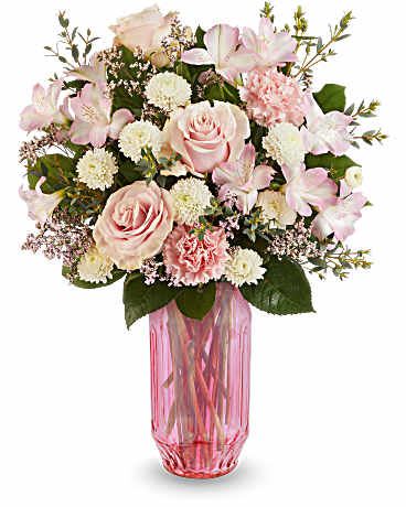 Pink roses and white flowers arranged in a pink glass vase