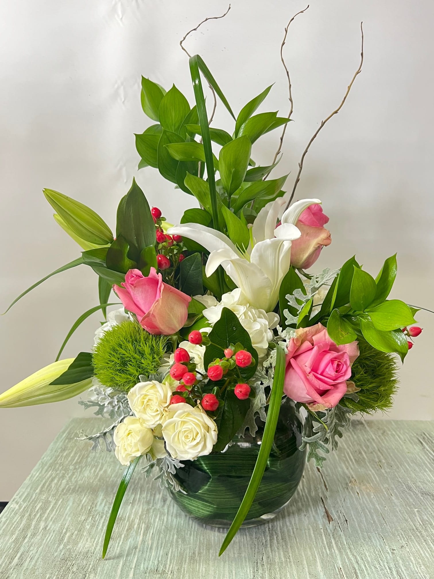 Pink and white roses with lilies in a glass vase