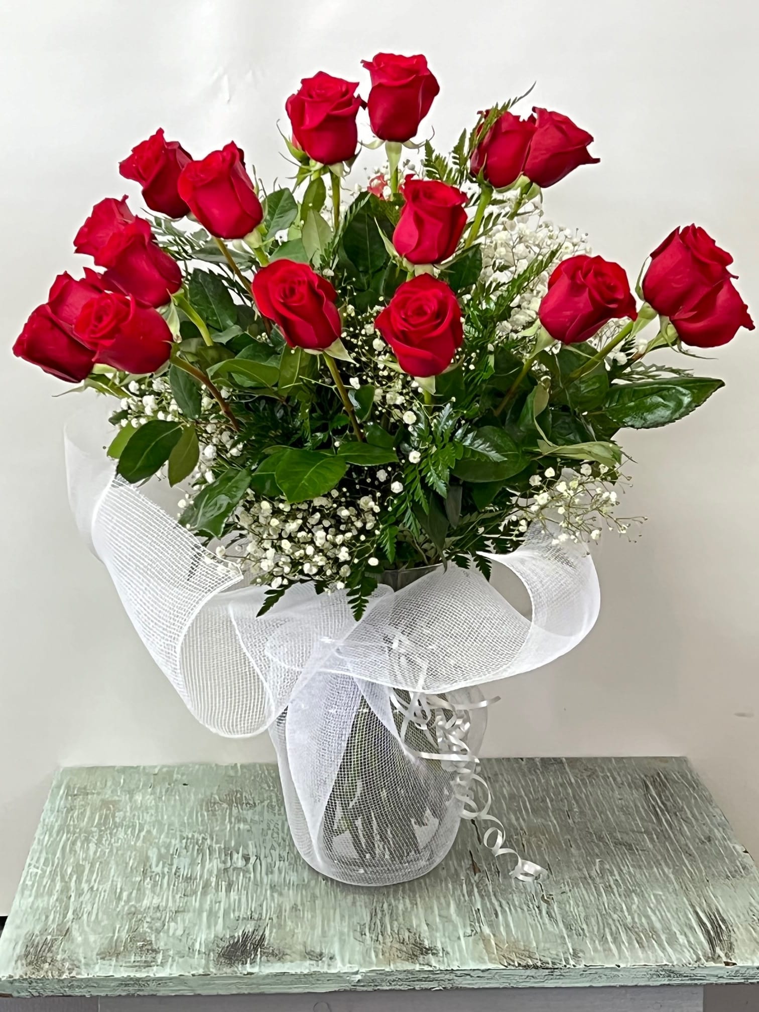 Bouquet of red roses in a clear vase with white ribbon