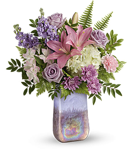 Bouquet of pink lilies, lavender roses, and purple flowers in a tall vase