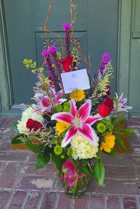 Colorful mixed flower arrangement in a glass vase with lilies and roses