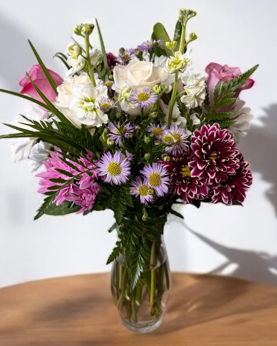 Mixed bouquet of white, pink, and purple flowers in a clear glass vase