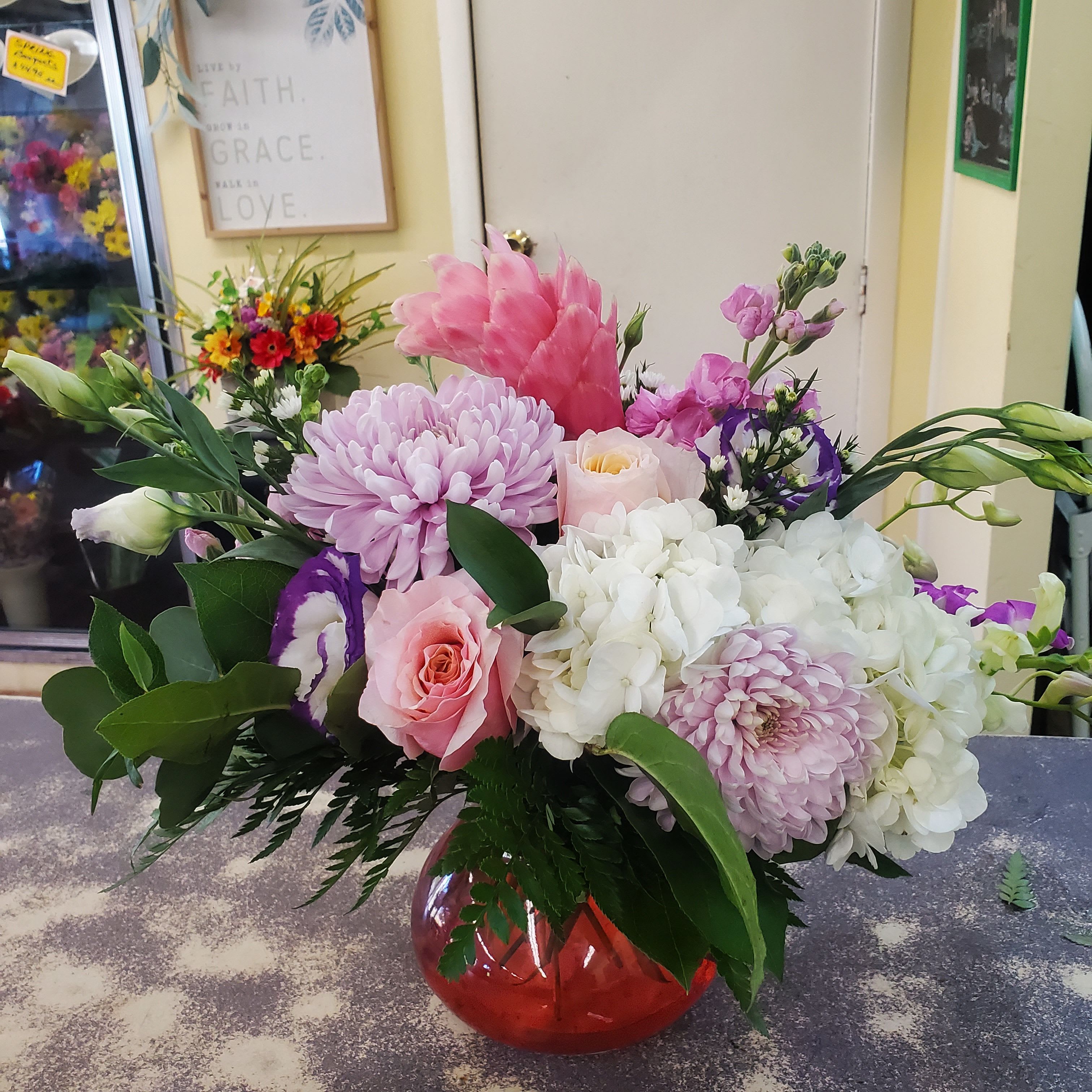 Pretty in Pink  - Short glass arrangement designed in shades of light pink,  lavender, white hydrangea and assorted natural greens. 