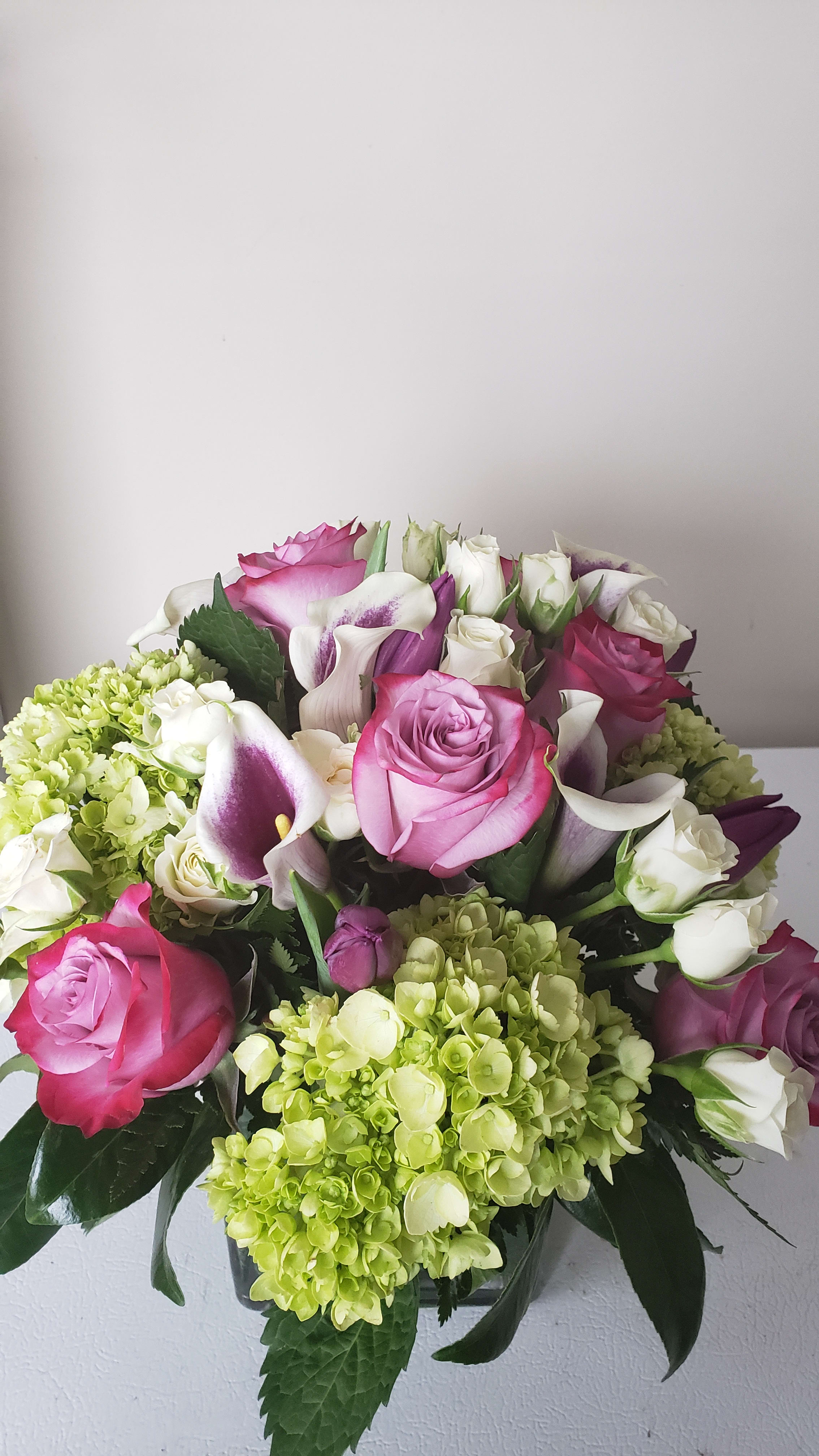 Bouquet of pink roses, white calla lilies, and green hydrangeas