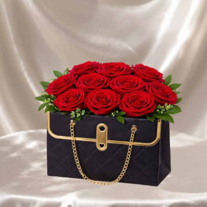 Midnight Rose Handbag™ - A chic handbag-style flower arrangement designed in a sleek black keepsake container, filled with lush red roses and finished with fresh greenery. Bold, modern, and ultra-elegant, this design is made to impress from the moment it arrives.  Each arrangement is Designer’s Choice, thoughtfully created with fresh seasonal blooms. Flower varieties and color tones may vary based on availability while preserving the overall style, structure, and luxurious presentation.  Perfect for Valentine’s Day, anniversaries, birthdays, romantic gestures, or sending a refined and unforgettable “I love you” surprise.  Same day flower delivery available in Southwest Florida, including Naples, Bonita Springs, and Fort Myers Beach.