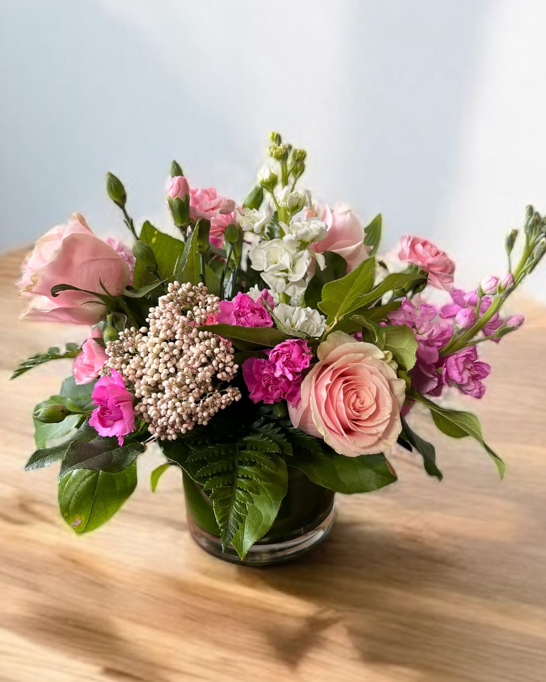 Pink and white mixed flower arrangement in a low glass vase