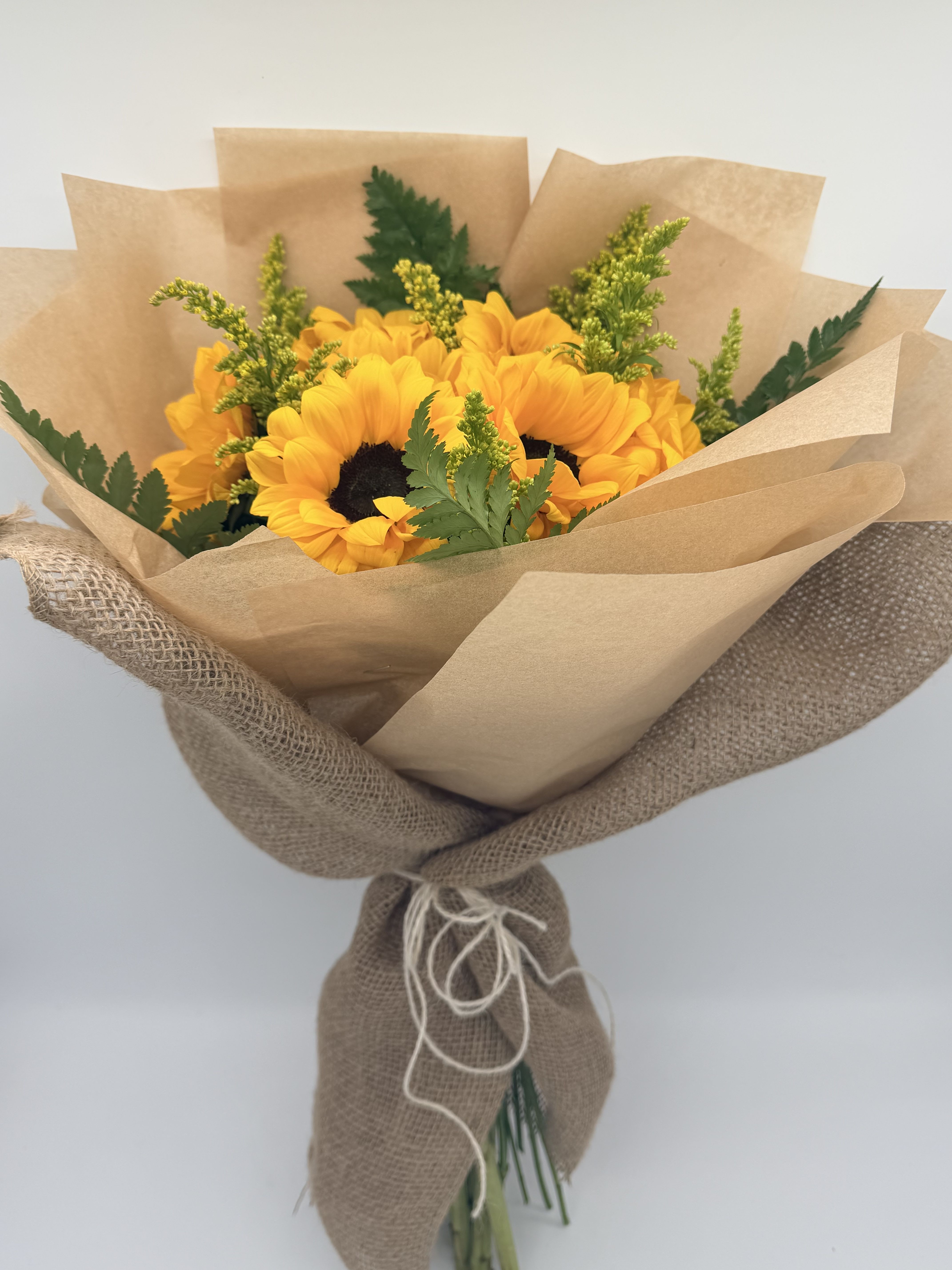 Bouquet of yellow sunflowers wrapped in brown paper and burlap
