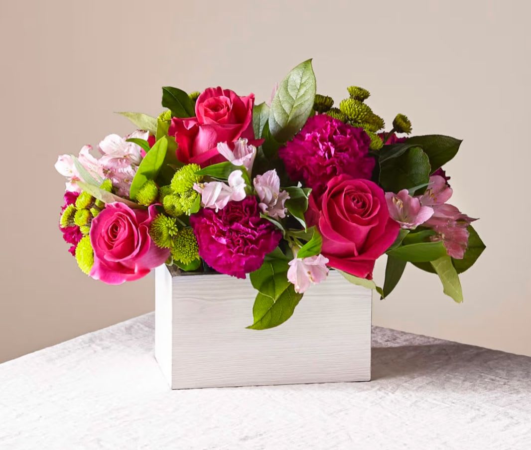 Pink roses and mixed blooms arranged in a white rectangular box