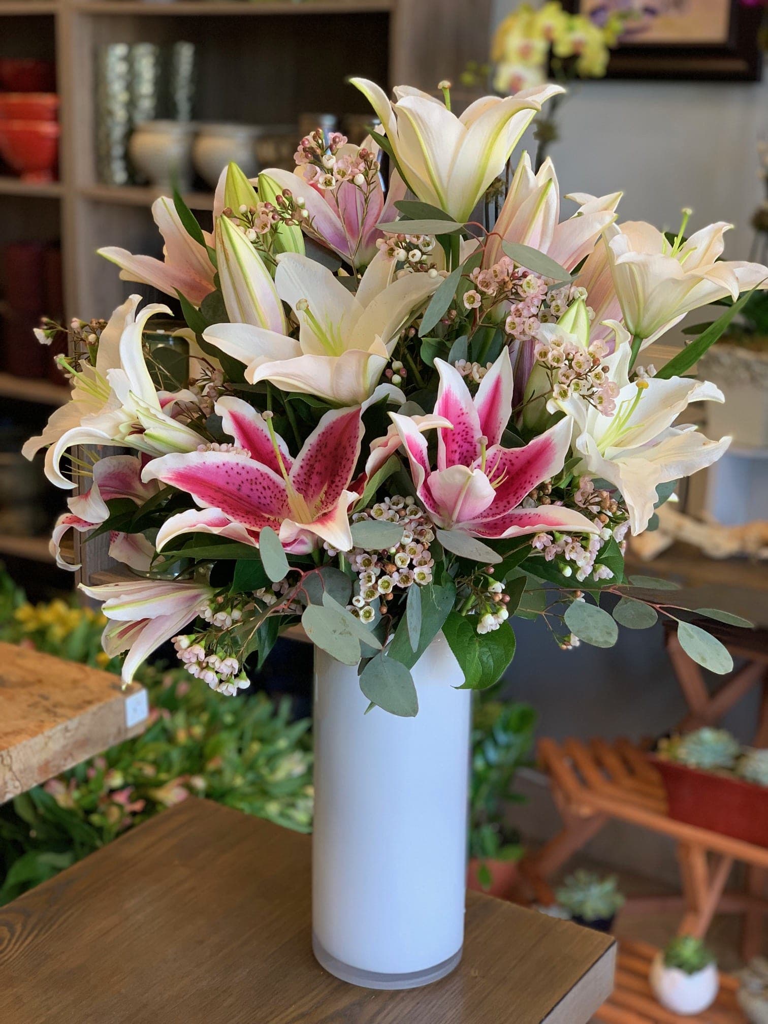 Bouquet of pink and white lilies in a tall white vase