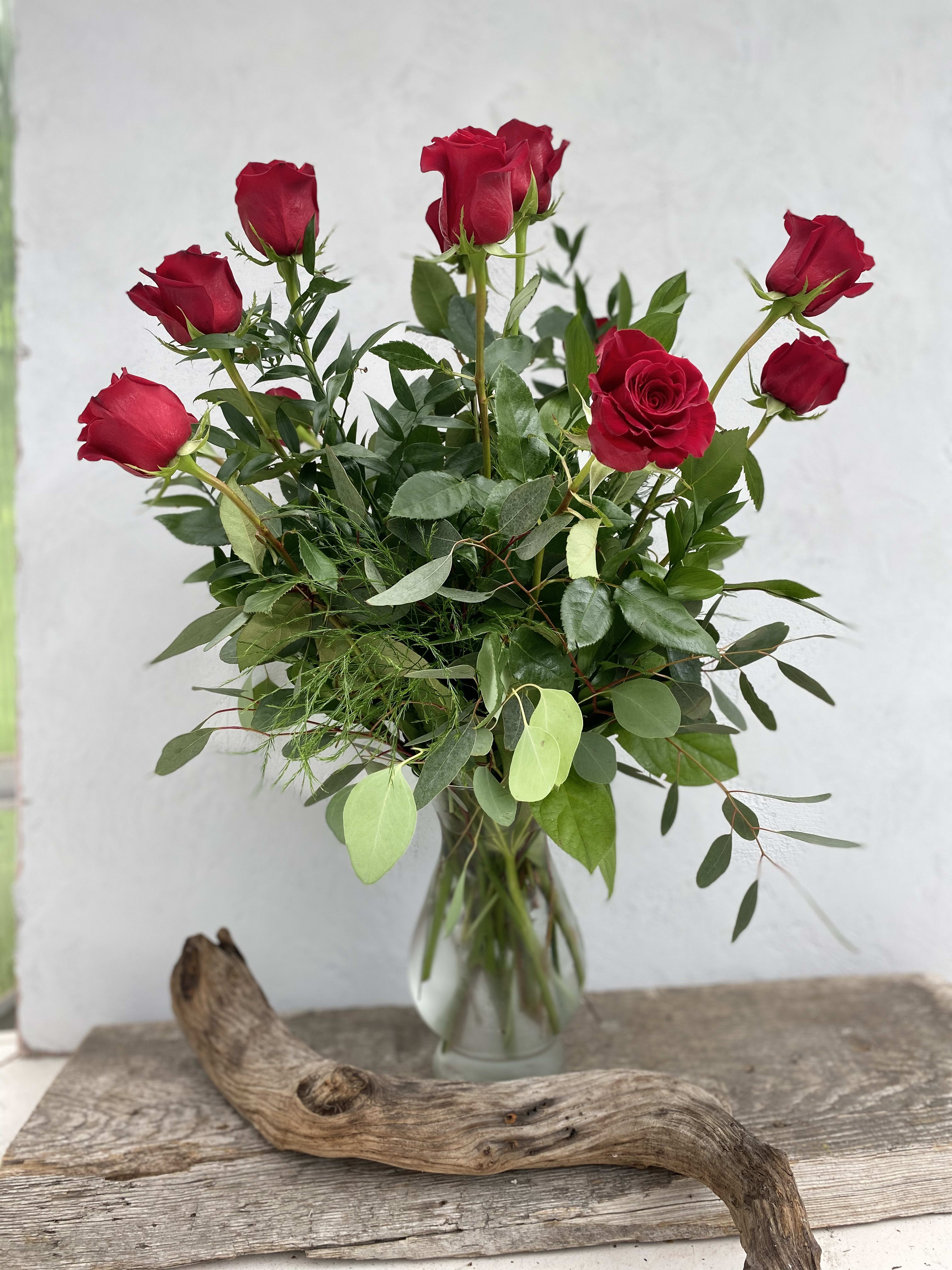 Red roses in a clear glass vase with mixed greenery