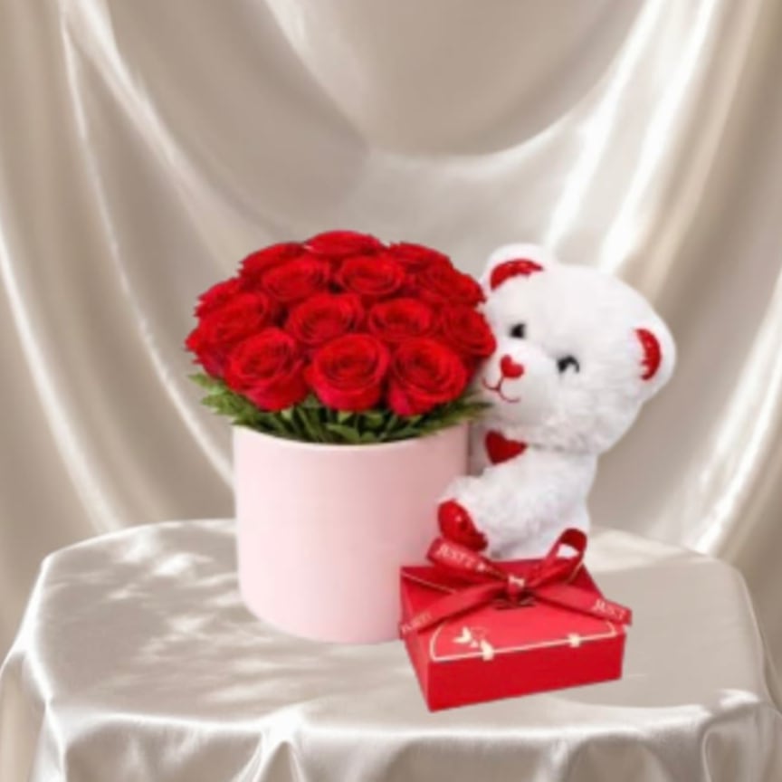 Red Rose &amp; Teddy Gift Box™ - A romantic arrangement featuring a lush arrangement of premium red roses beautifully designed in a soft pink hat box, paired with an adorable plush teddy bear and a sweet chocolate gift. A classic combination that delivers love, warmth, and a big smile.  Each piece is Designer’s Choice, created with fresh seasonal blooms. Flowers and colors may vary based on availability while maintaining the overall style and quality.  Better for: Valentine’s Day, anniversaries, romantic surprises, I love you, birthdays, just because.