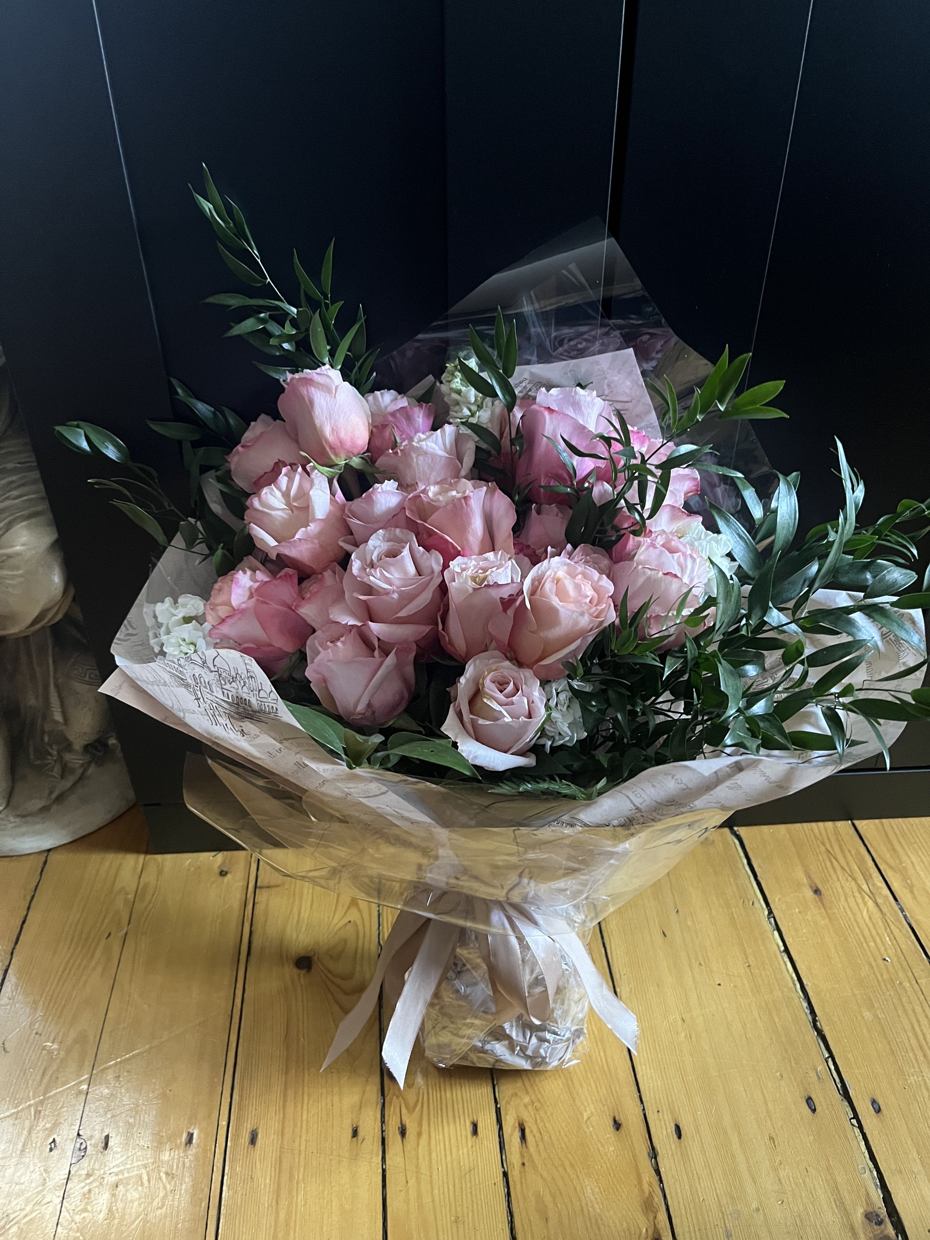 Bouquet of pale pink roses wrapped in paper with a ribbon