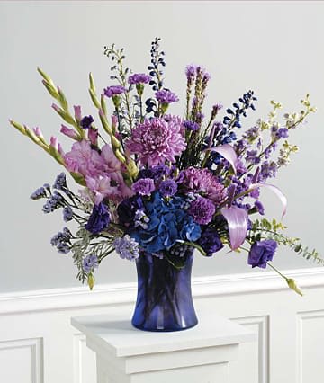 Purple and blue floral arrangement in a dark blue vase