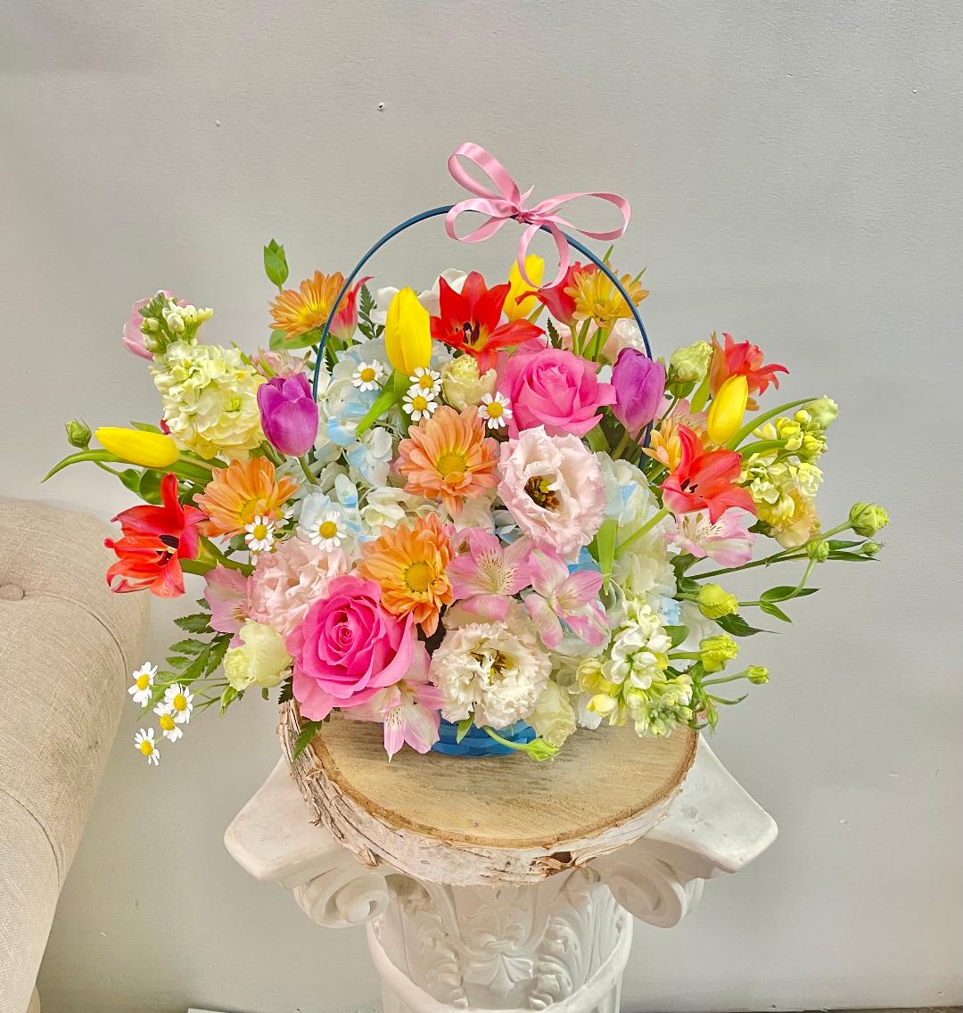 Colorful mixed flower basket with a pink ribbon handle