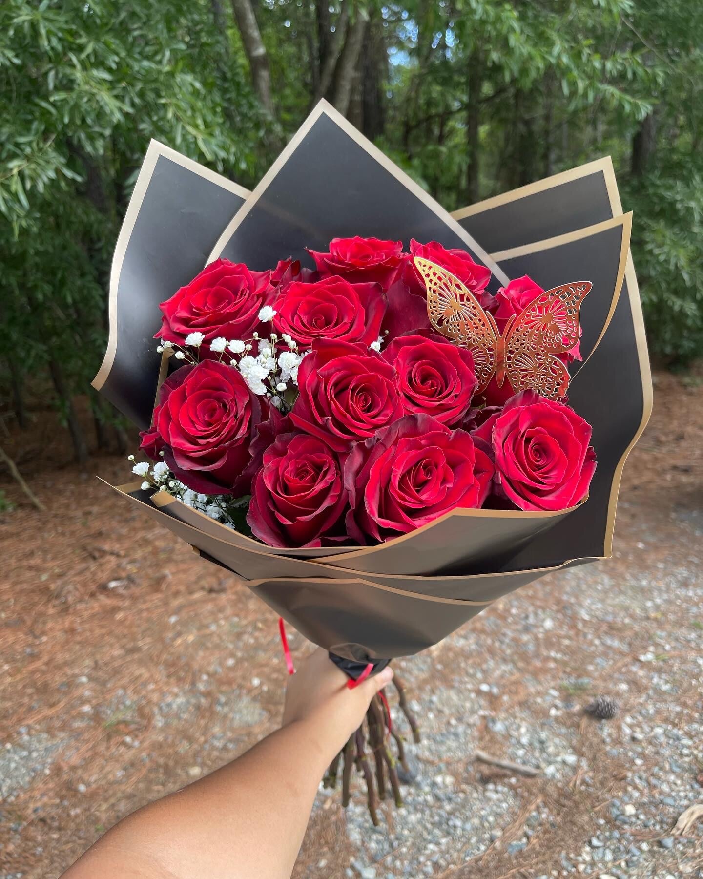 Bouquet of red roses wrapped in black paper with a butterfly accent