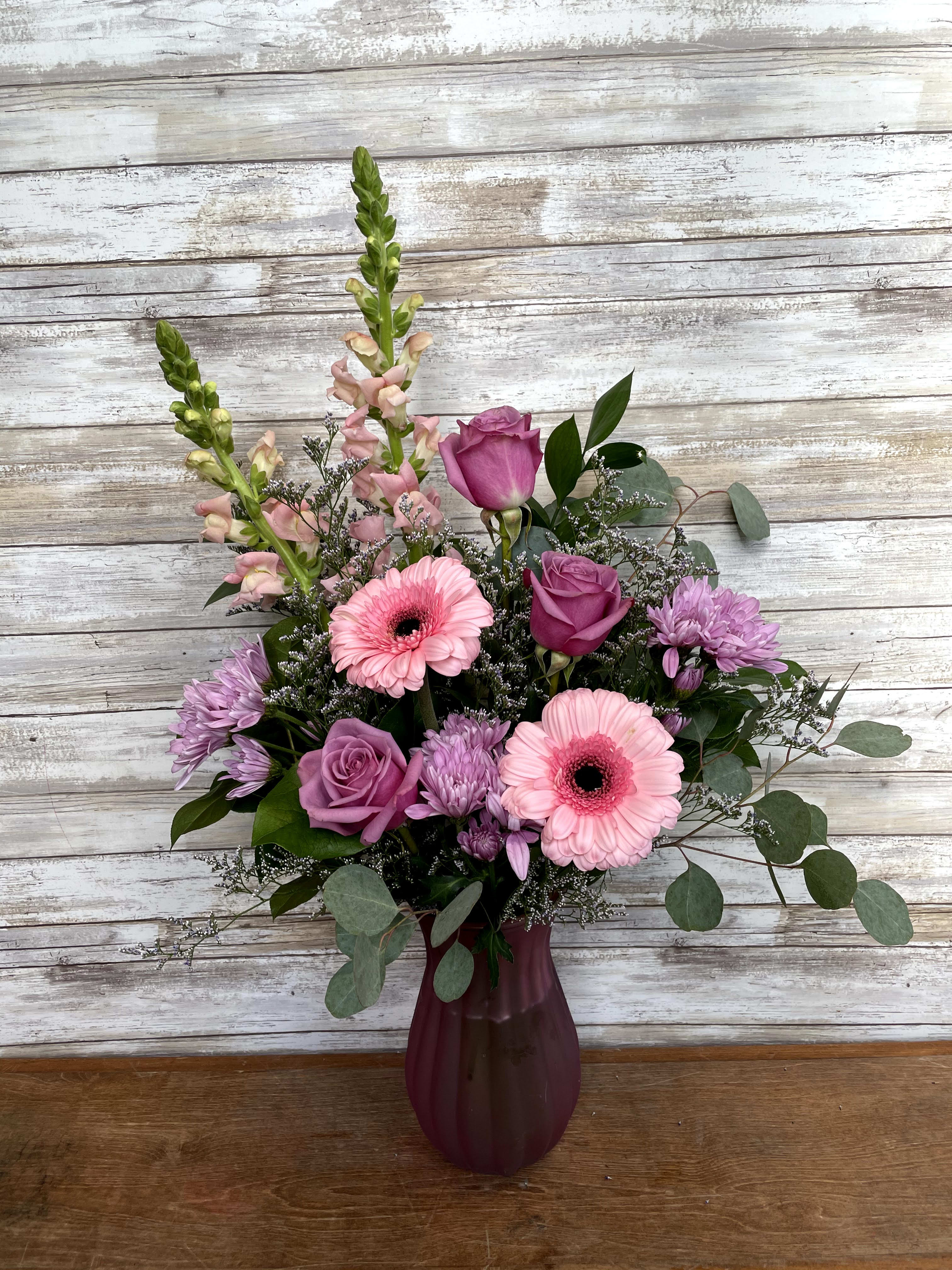 Pink and purple mixed flower arrangement in a burgundy vase