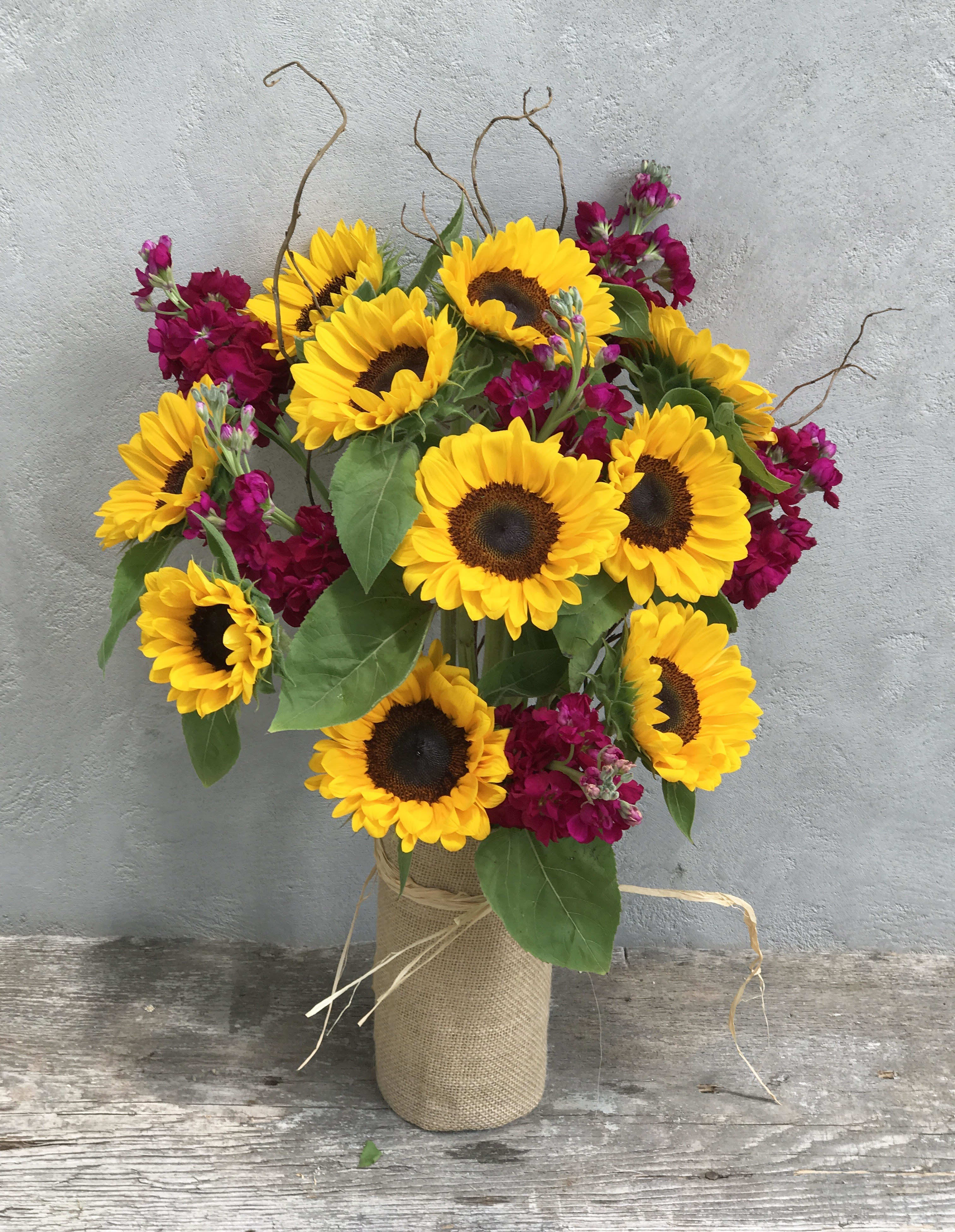 Sunflower bouquet with magenta flowers in a burlap-wrapped vase