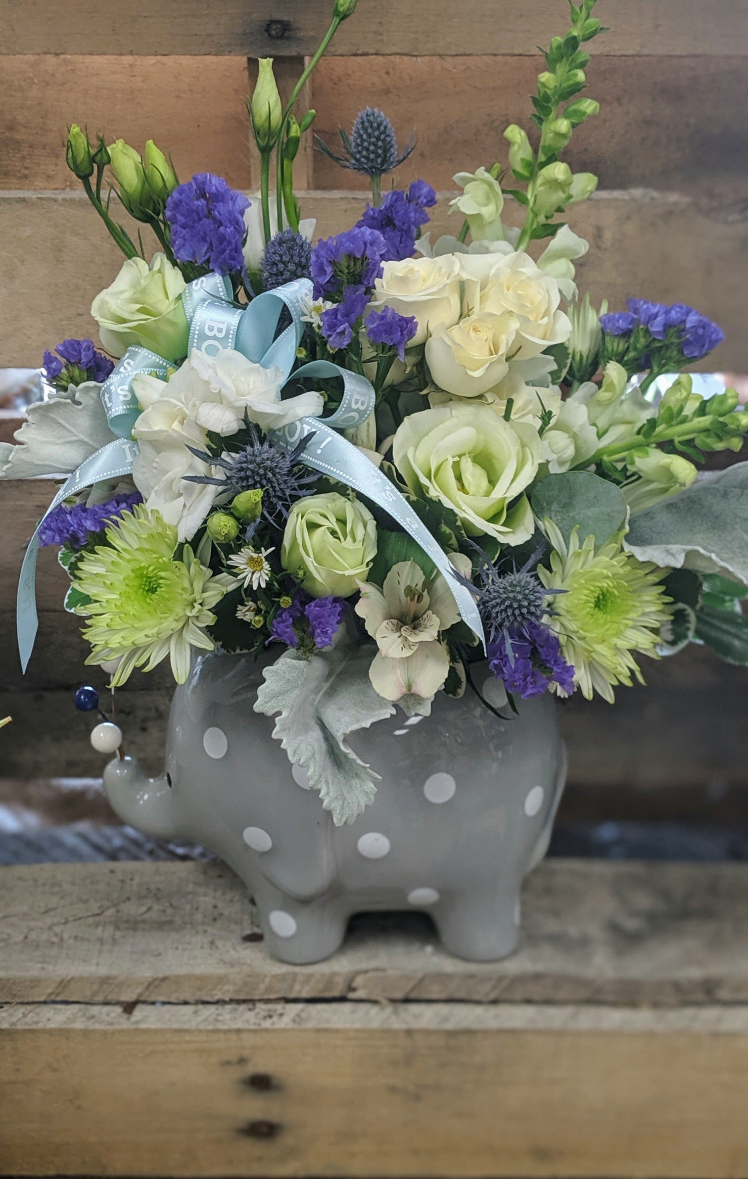 Mixed bouquet in a gray polka-dot elephant vase with blue ribbon