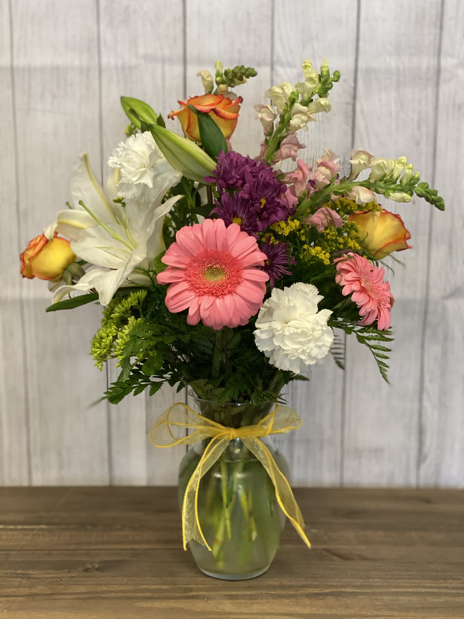 Mixed bouquet in a glass vase with a yellow ribbon