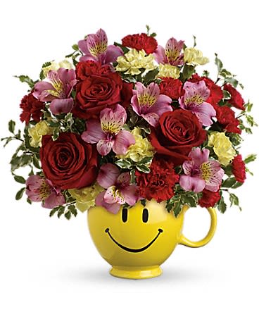 Red and pink mixed bouquet in a yellow smiley-face mug