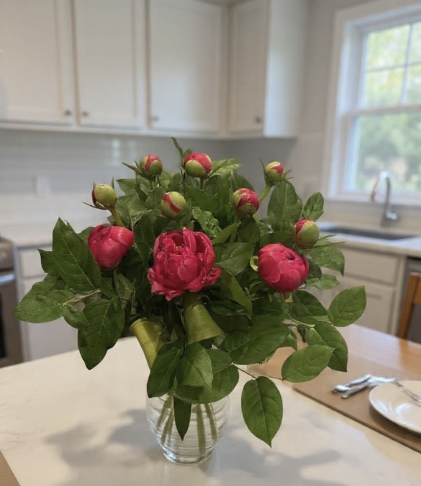 Mother’s Day Peony Bouquet  - Arrangement measures approximately 19”H  Luxury Peony Bouquet is designed to make Mom feel truly celebrated. Featuring premium peonies in vibrant pink hues paired with lush greenery and styled in a chic glass vase, this arrangement brings effortless elegance to any home. Peonies are cherished for their large, cloud-like blooms and delicate fragrance, symbolizing love, happiness, and prosperity. Each bouquet is carefully arranged with a blend of blooming flowers and fresh buds so the arrangement continues to open beautifully day after day. Whether you’re sending love across town or surprising Mom in person, this bouquet creates a memorable Mother’s Day moment she won’t forget. Perfect For * Mother’s Day gifts * Elegant home décor * Birthday flower delivery * Thank-you or thinking-of-you surprises  