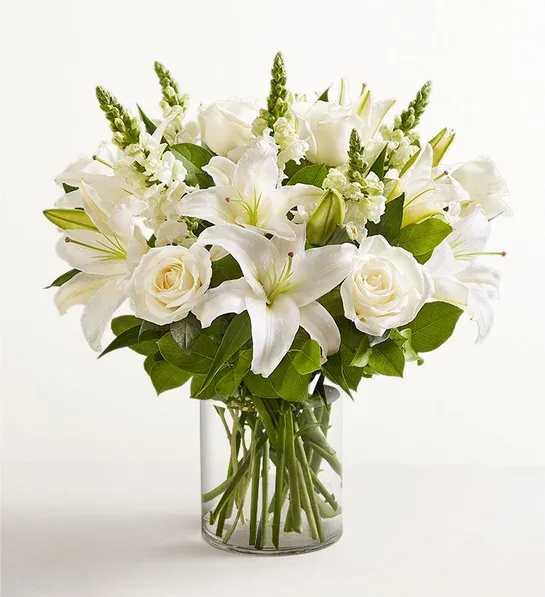 White lilies and roses arranged in a clear glass vase