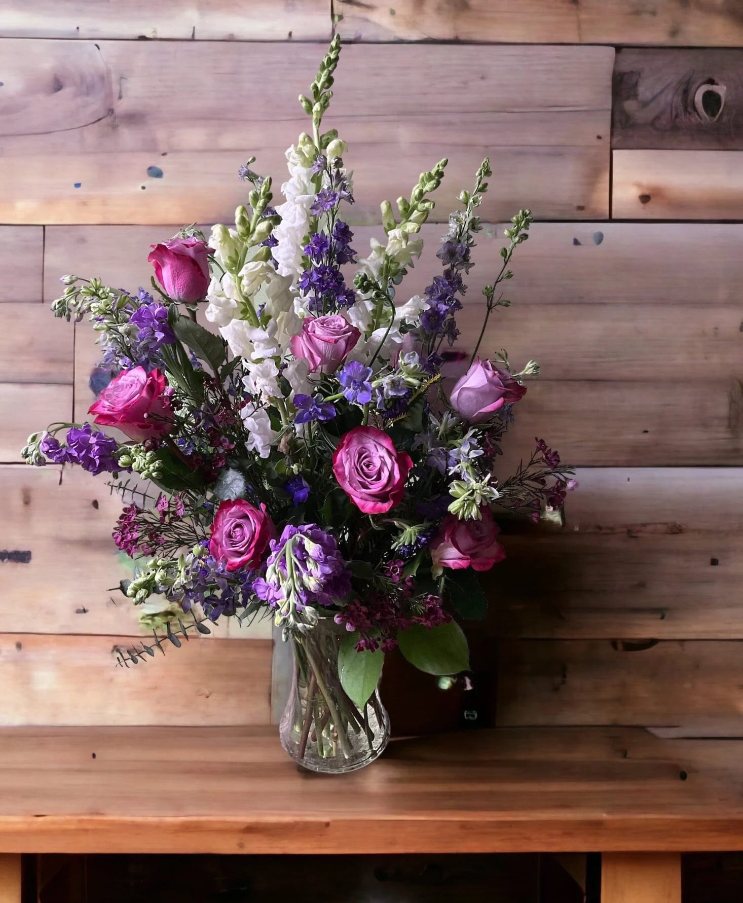 Pink and purple roses with white and purple snapdragons in a glass vase