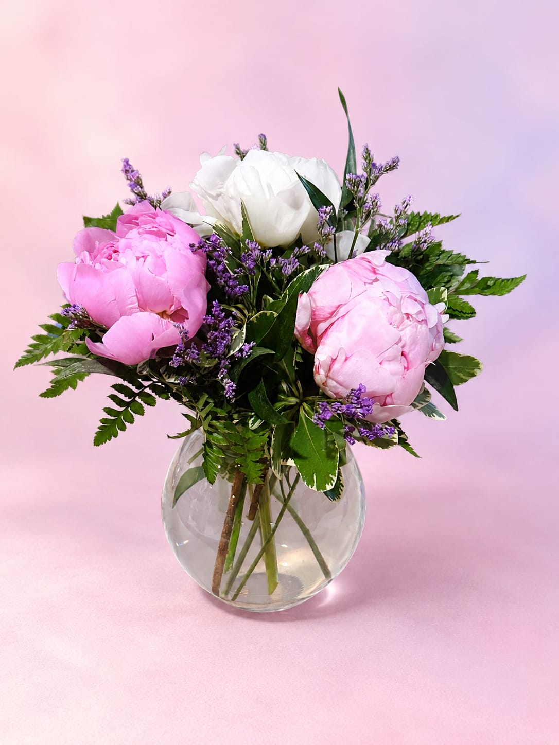 Peony Petal Dream - Soft, romantic, and effortlessly elegant, Peony Petal Dreams showcases lush pink and white peonies paired with delicate lavender accents and fresh greenery for a naturally graceful design. Arranged in a clear glass bubble vase, this bouquet highlights the beauty of premium peonies with a light garden-inspired touch. Full of soft texture and timeless charm, it’s a beautiful choice for Mother’s Day, anniversaries, birthdays, or simply celebrating someone special with classic blooms and delicate beauty.