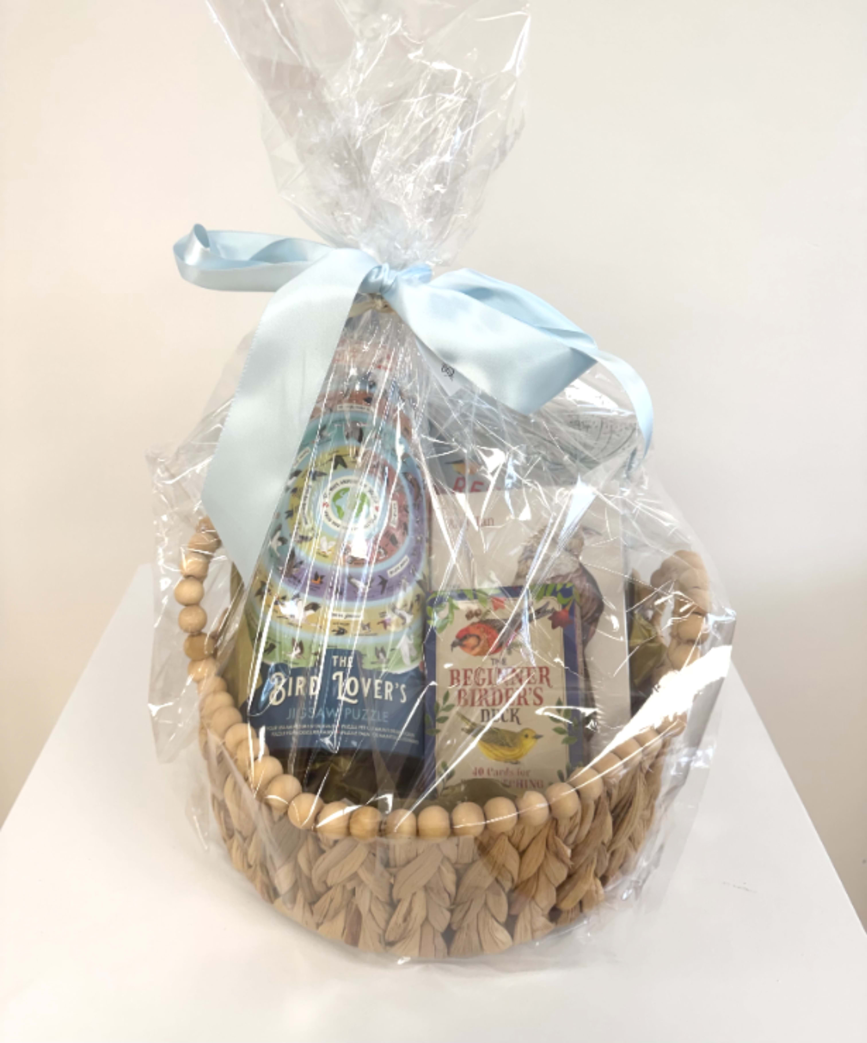 Gift basket with bird-themed books wrapped in clear cellophane and a blue ribbon