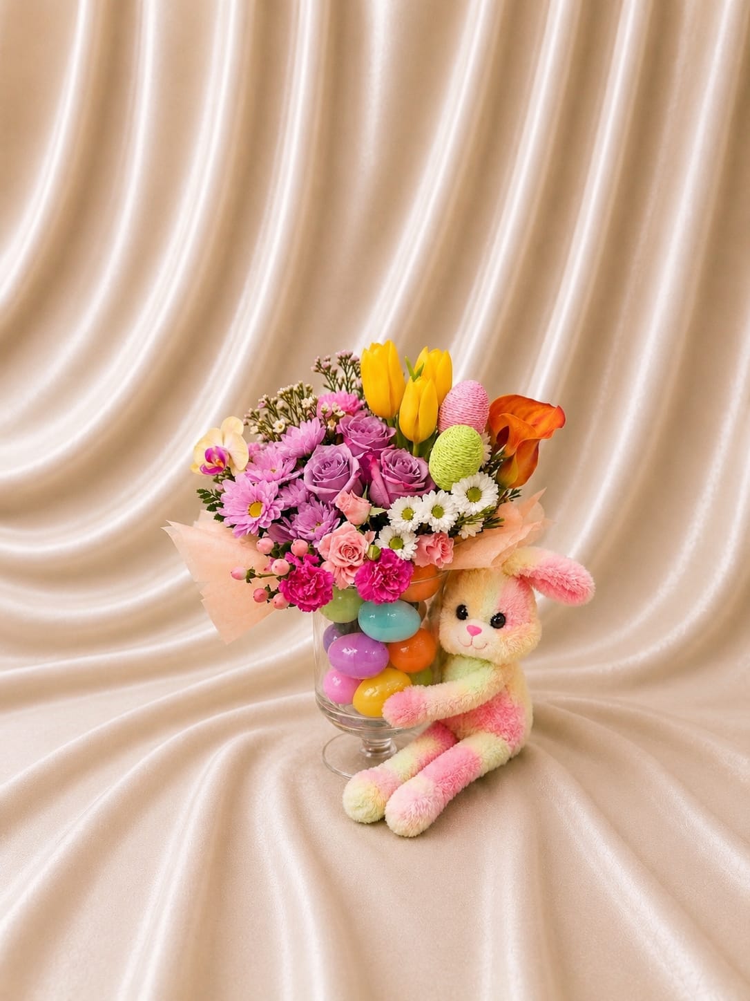 Colorful bouquet in a glass vase with a plush bunny beside it