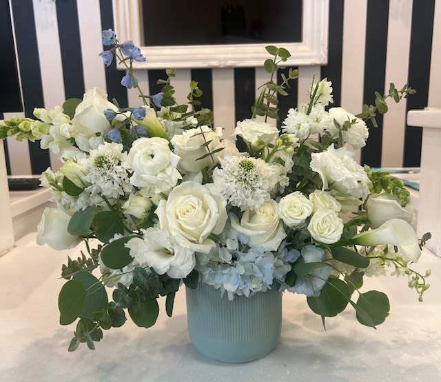 White roses and calla lilies in a pale blue vase with blue accents
