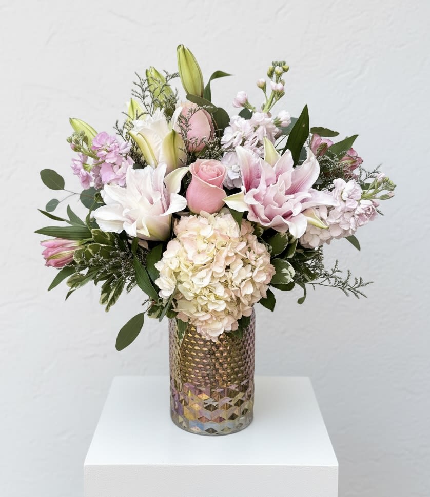 Norma Ann  - A pretty in pink vase arrangement perfect for Mother’s Day! A pink iridescent glass vase filled with a pink hydrangea, light pink double lilies, lavender stock, light pink roses and pink alstroemeria. 