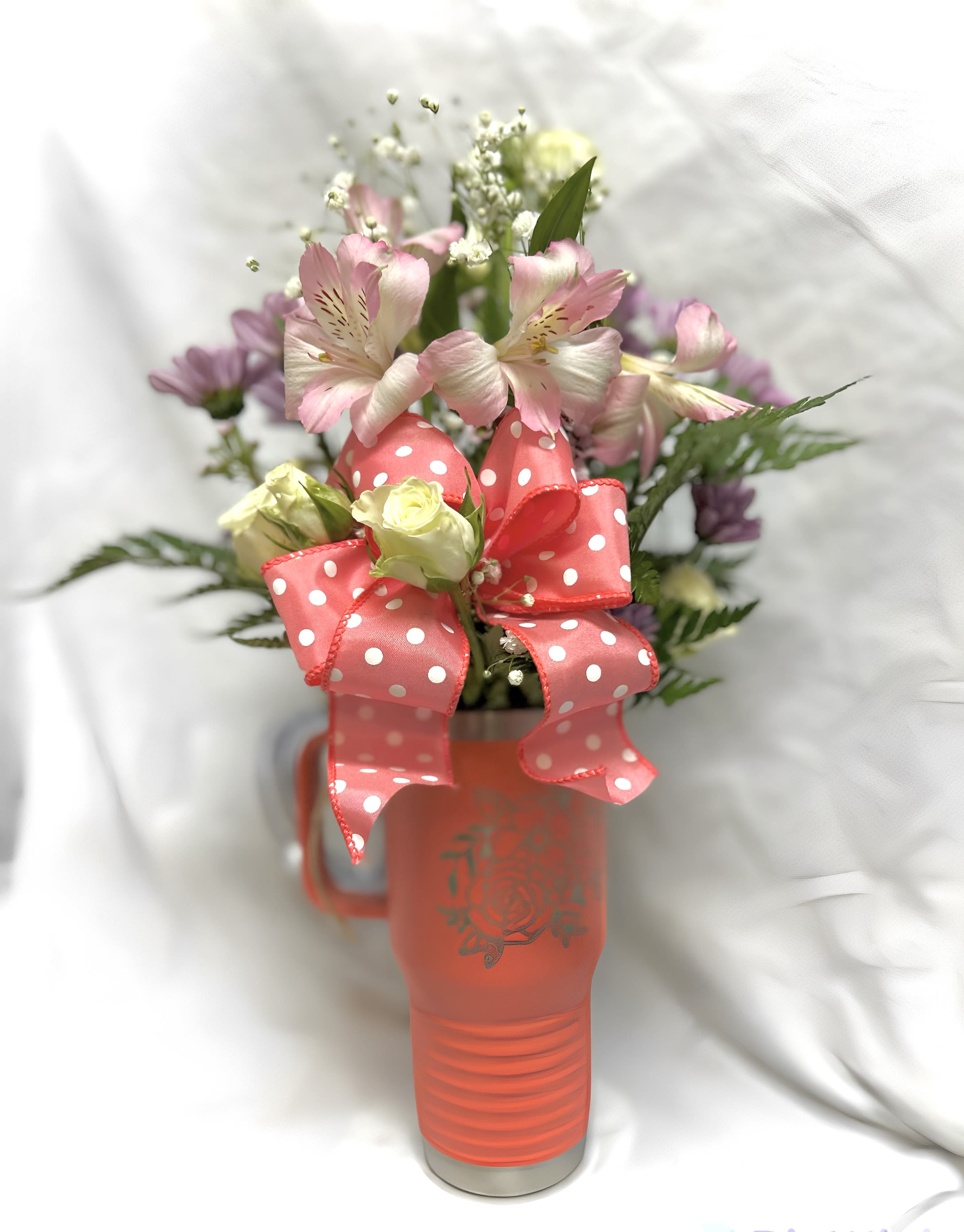 Pink and white flowers in a coral mug with a polka-dot ribbon