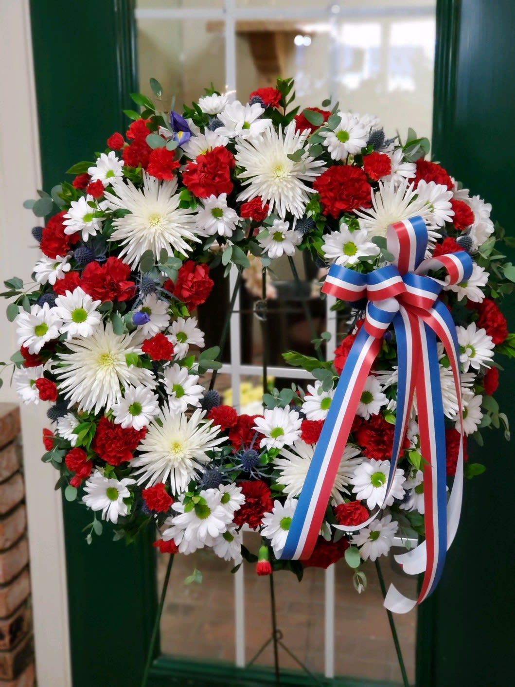 Red, white, and blue floral wreath with a ribbon bow