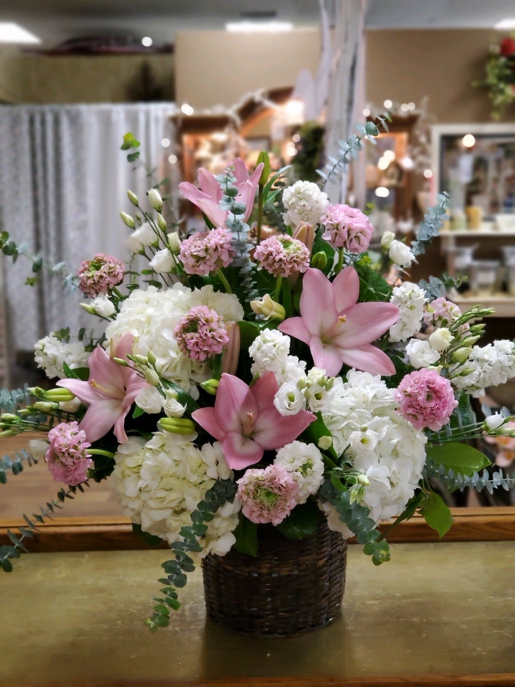 Pink lilies and white hydrangeas in a dark woven basket