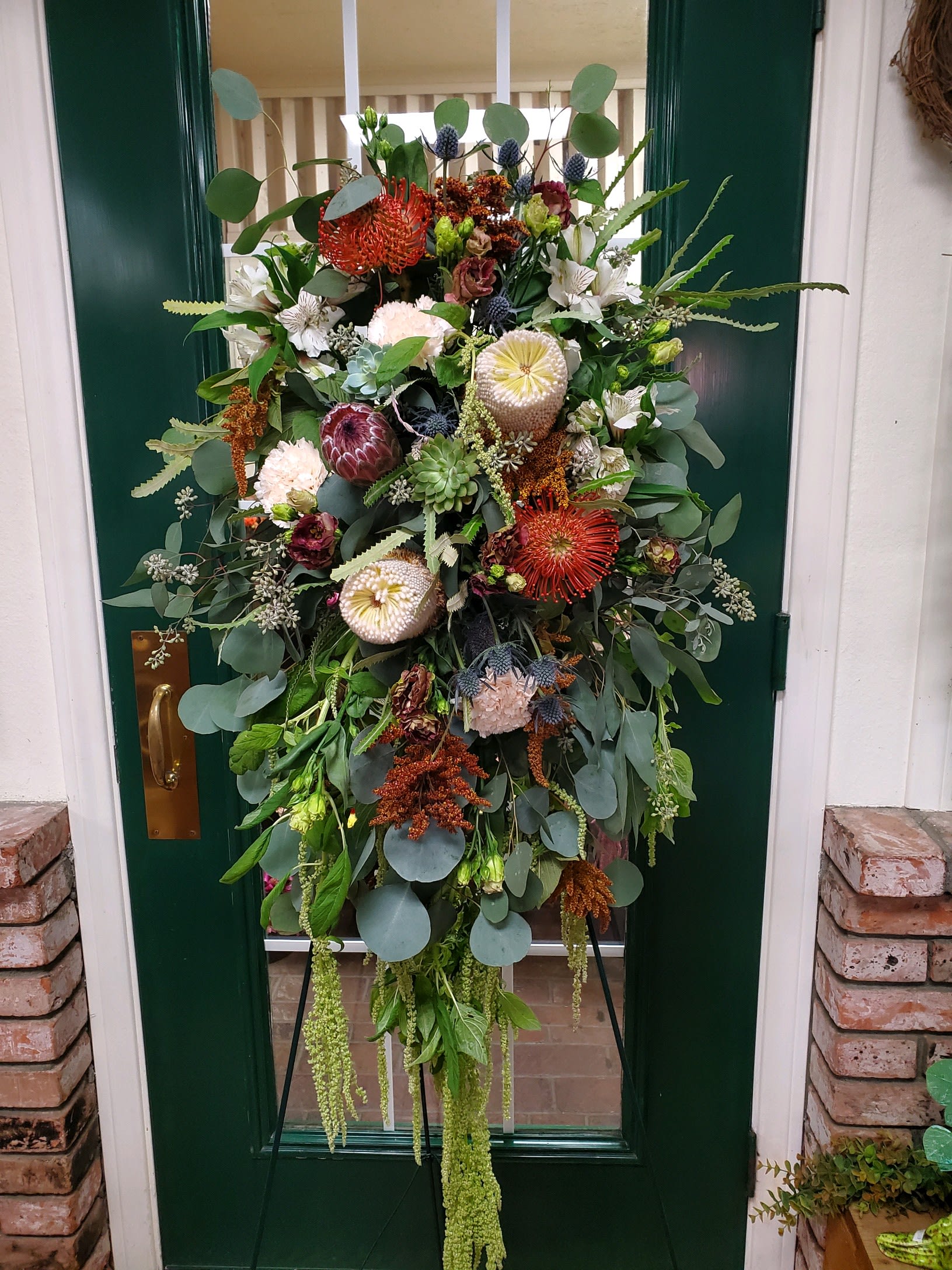 Large floral wreath with mixed blooms and greenery on a stand