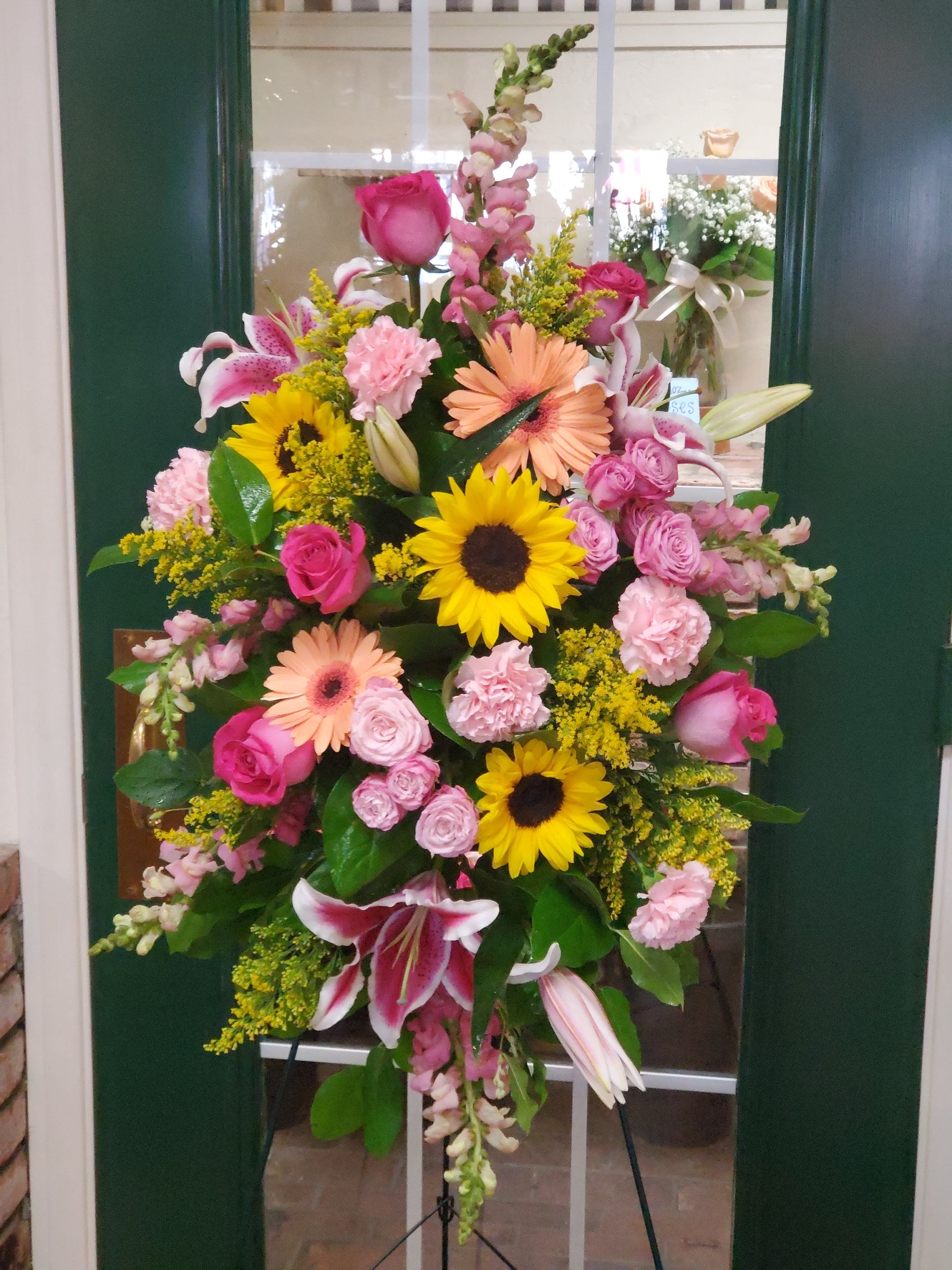 Large standing floral spray with pink, yellow, and peach blooms