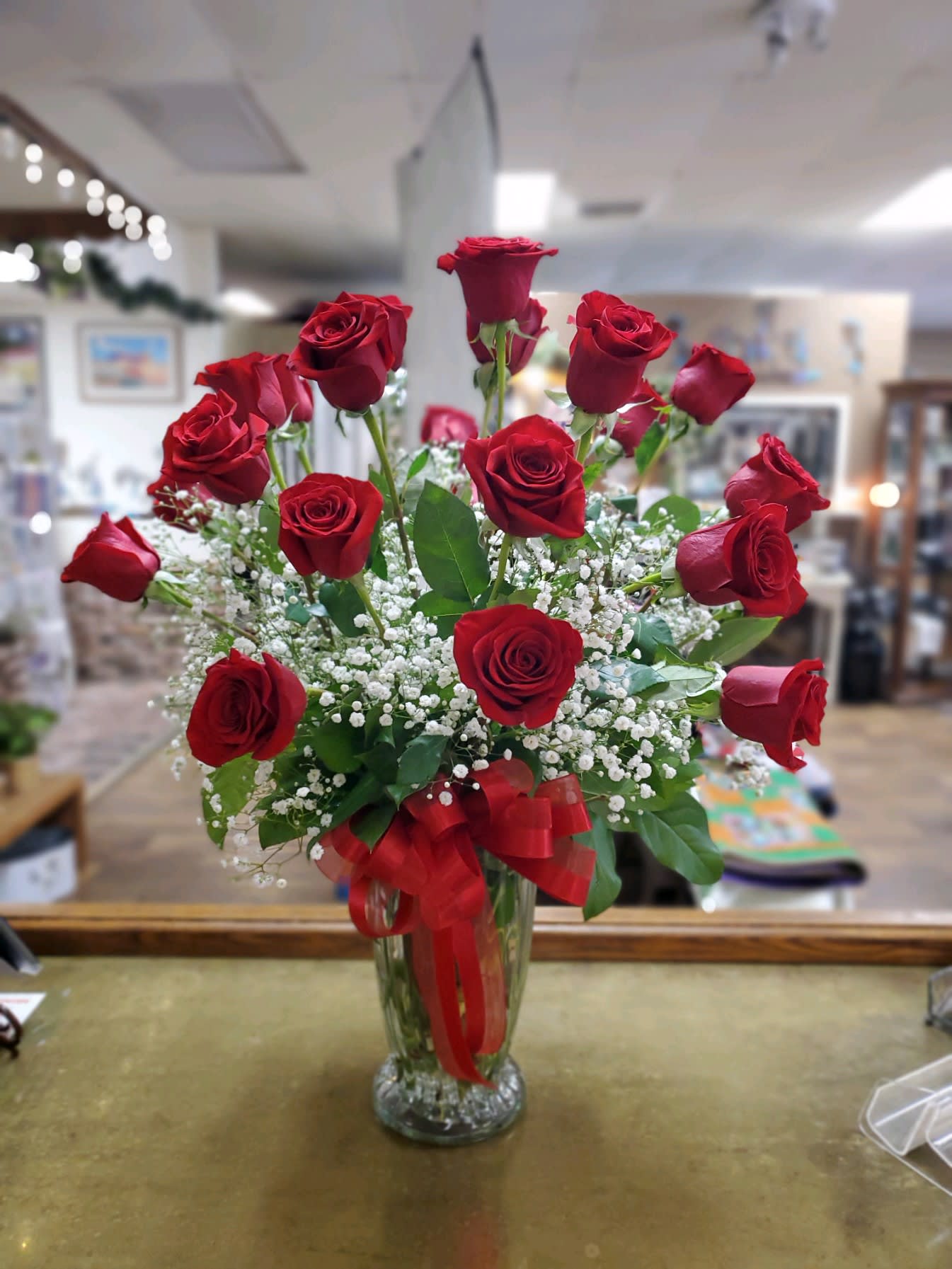 Red roses arranged in a clear glass vase with a red ribbon