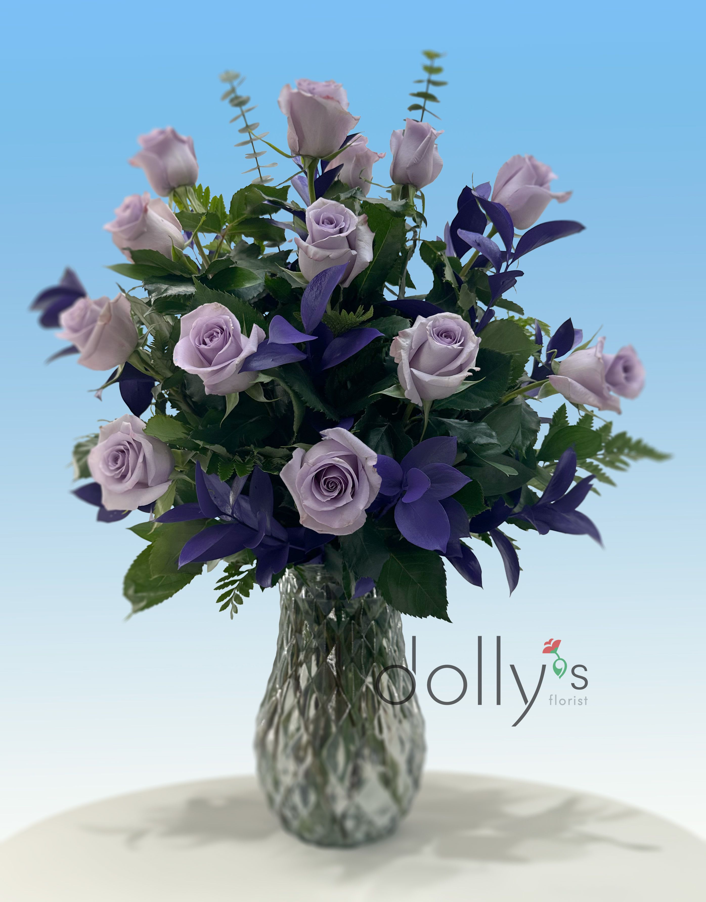 Lavender roses and dark purple flowers in a clear glass vase