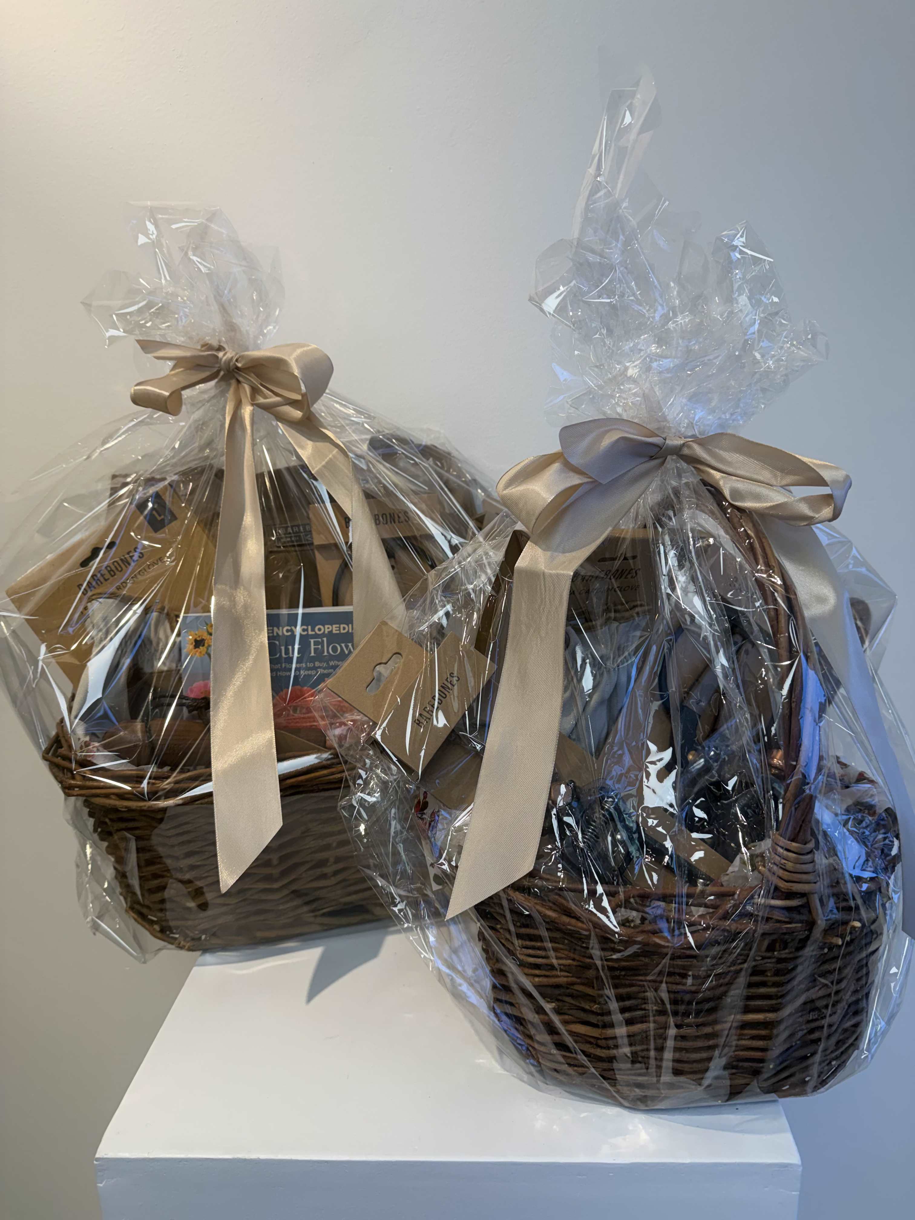 Two wrapped gift baskets with satin bows and books inside