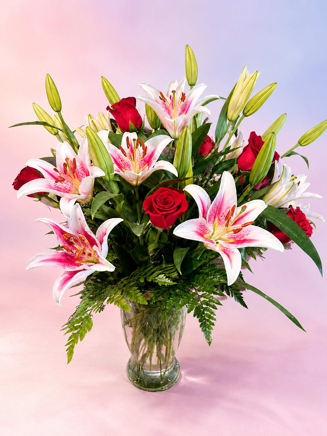 Stargazer Romance - Bold, elegant, and undeniably romantic, Stargazer Romance features stunning pink stargazer lilies paired with classic red roses for a timeless expression of love and beauty. Accented with lush greenery and surrounded by fresh lily buds ready to bloom, this arrangement is full of texture, fragrance, and dramatic color.