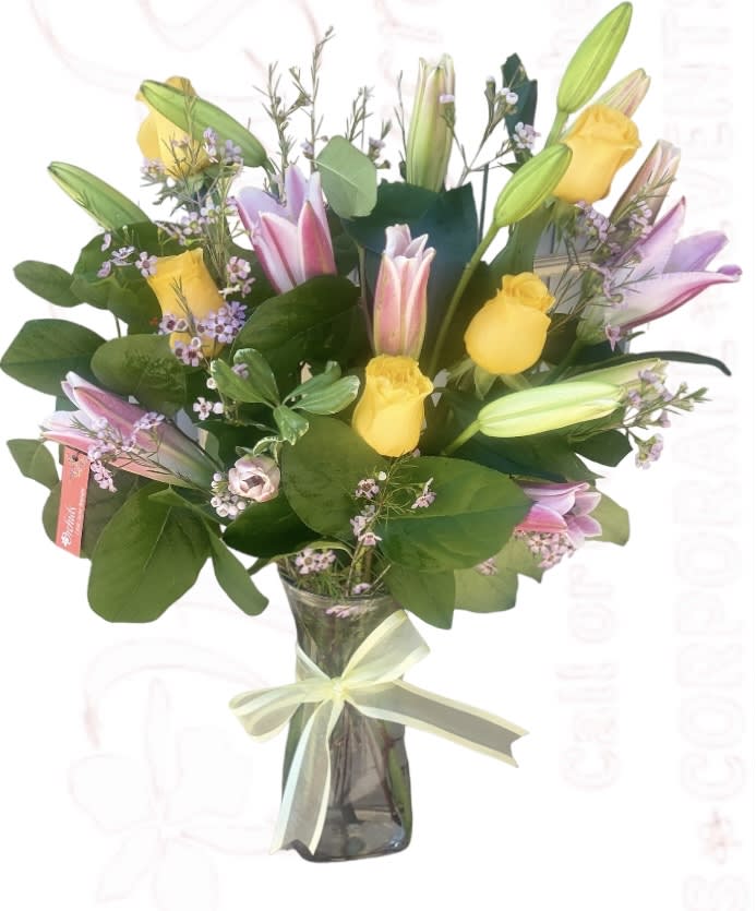 Bouquet of yellow roses and pink lilies in a glass vase