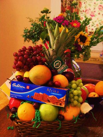 Fruit basket with a floral arrangement and a box of chocolates