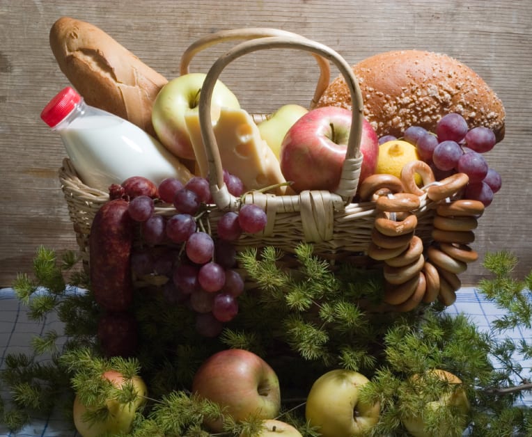Basket of bread, apples, grapes, cheese, and a milk bottle