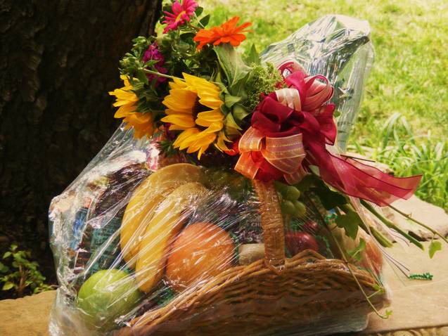Basket gift with sunflowers and fruit wrapped in clear cellophane