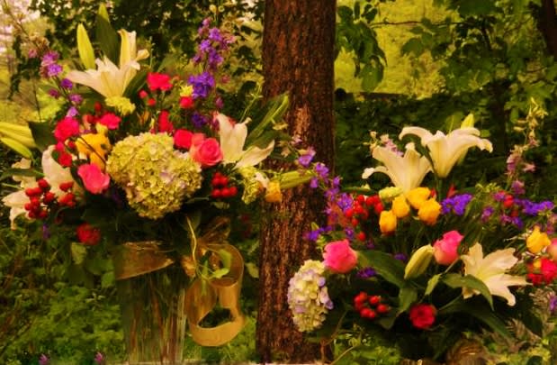 Two colorful floral arrangements with lilies, roses, and hydrangeas outdoors