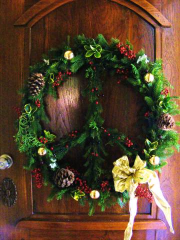Christmas wreath with pinecones, red berries, and a gold bow on a wooden door