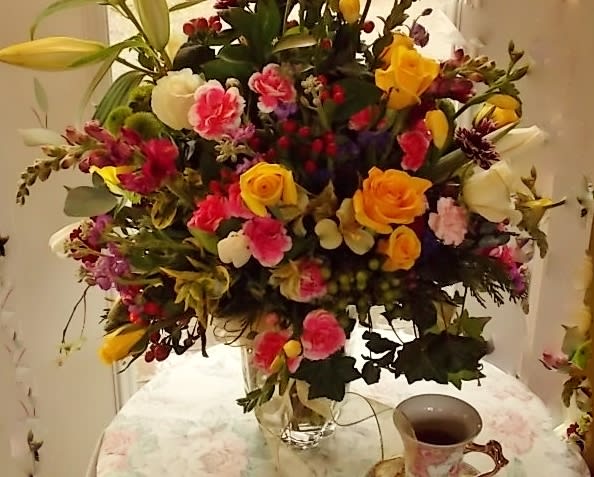 Large mixed bouquet in a clear glass vase with yellow, pink, and white flowers