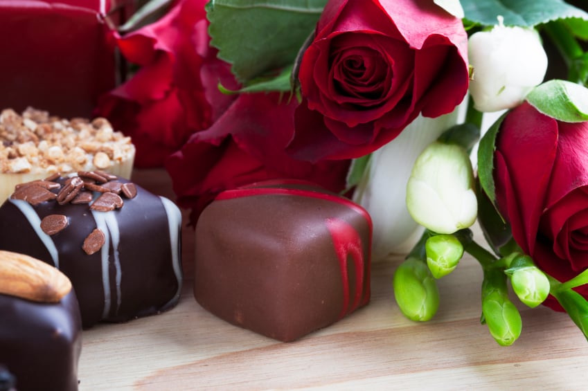 Red roses with assorted chocolates on a wooden surface